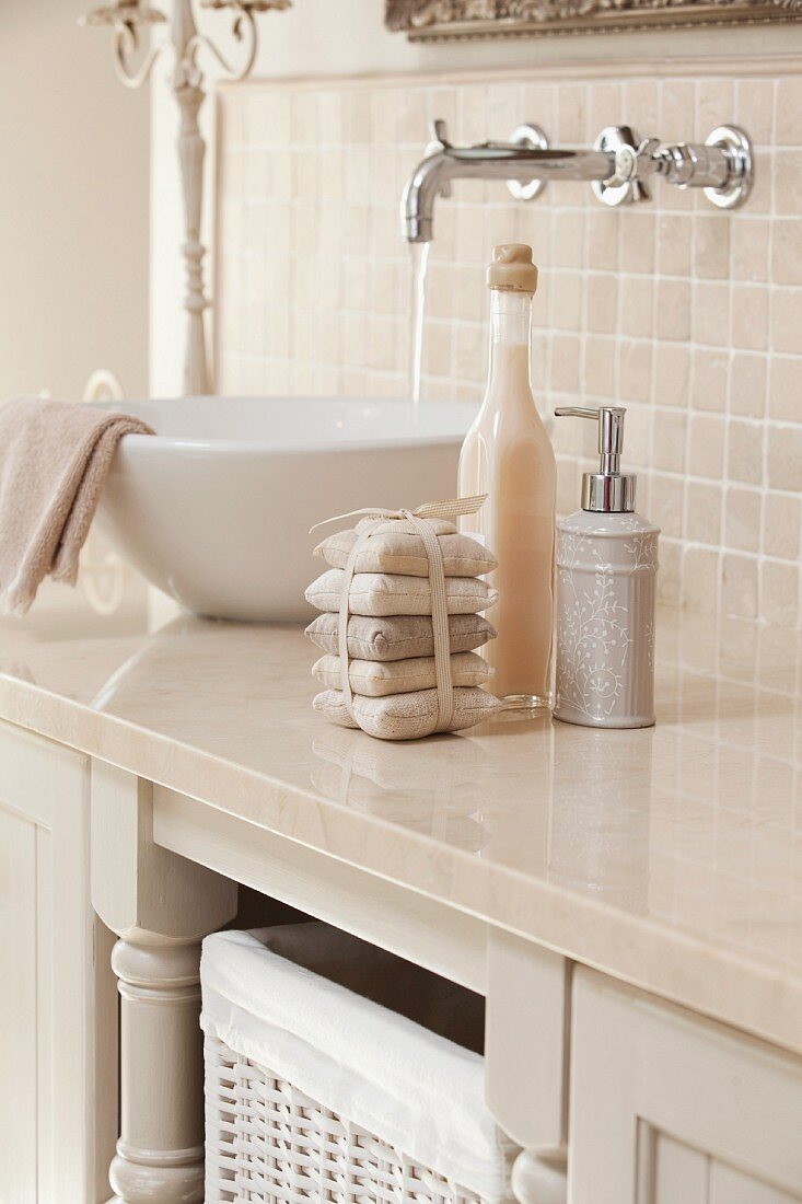 Detail of vintage-effect, designer-style washstand with white basin on sand-coloured stone counter