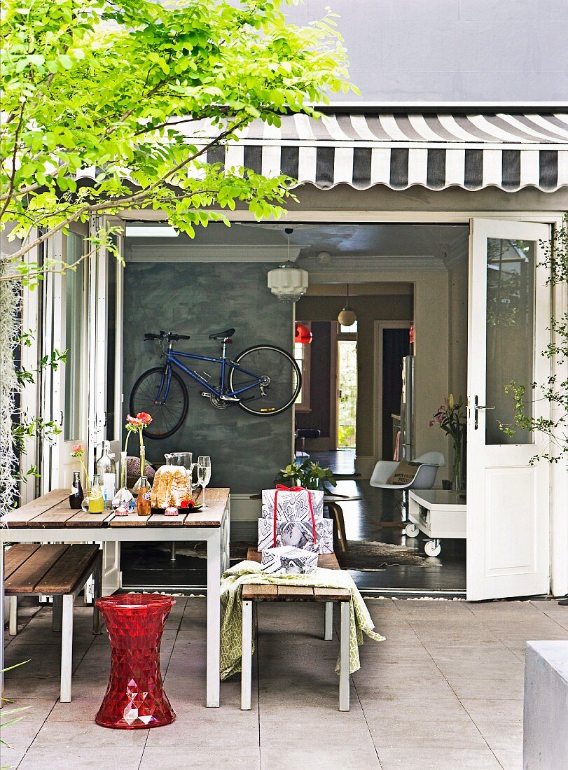 Gedeckter Tisch im Innenhof mit Blick in den offenen Wohnbereich, an der Wand hängt ein Fahrrad