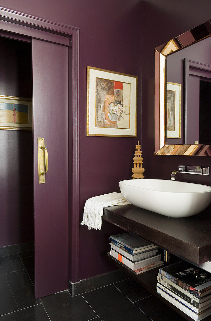 Moderner Waschtisch mit weisser Schüssel auf Holzplatte in lila getöntem Bad mit offener Schiebetür in gleicher Farbe