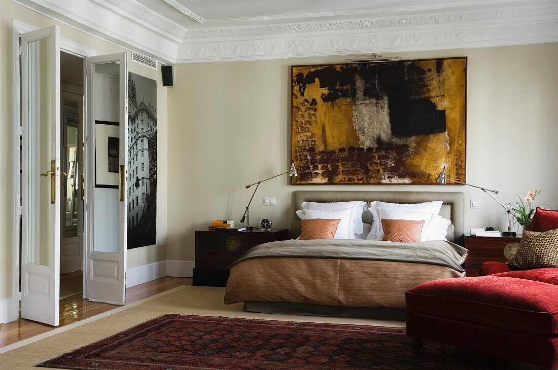 Grand bedroom with open double doors and double bed against wall below modern artwork