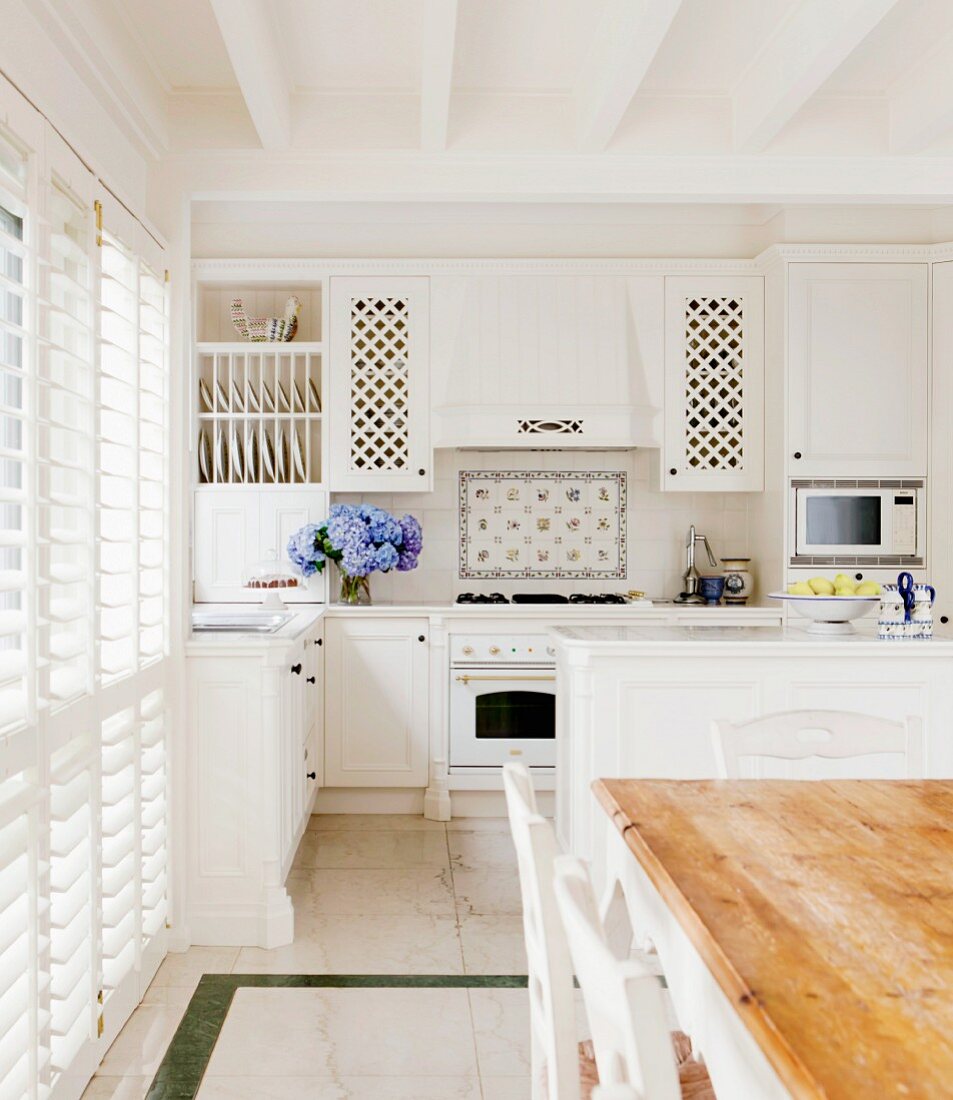 weiße Einbauküche im romantischen Landhausstil mit weißer Holzbalkendecke