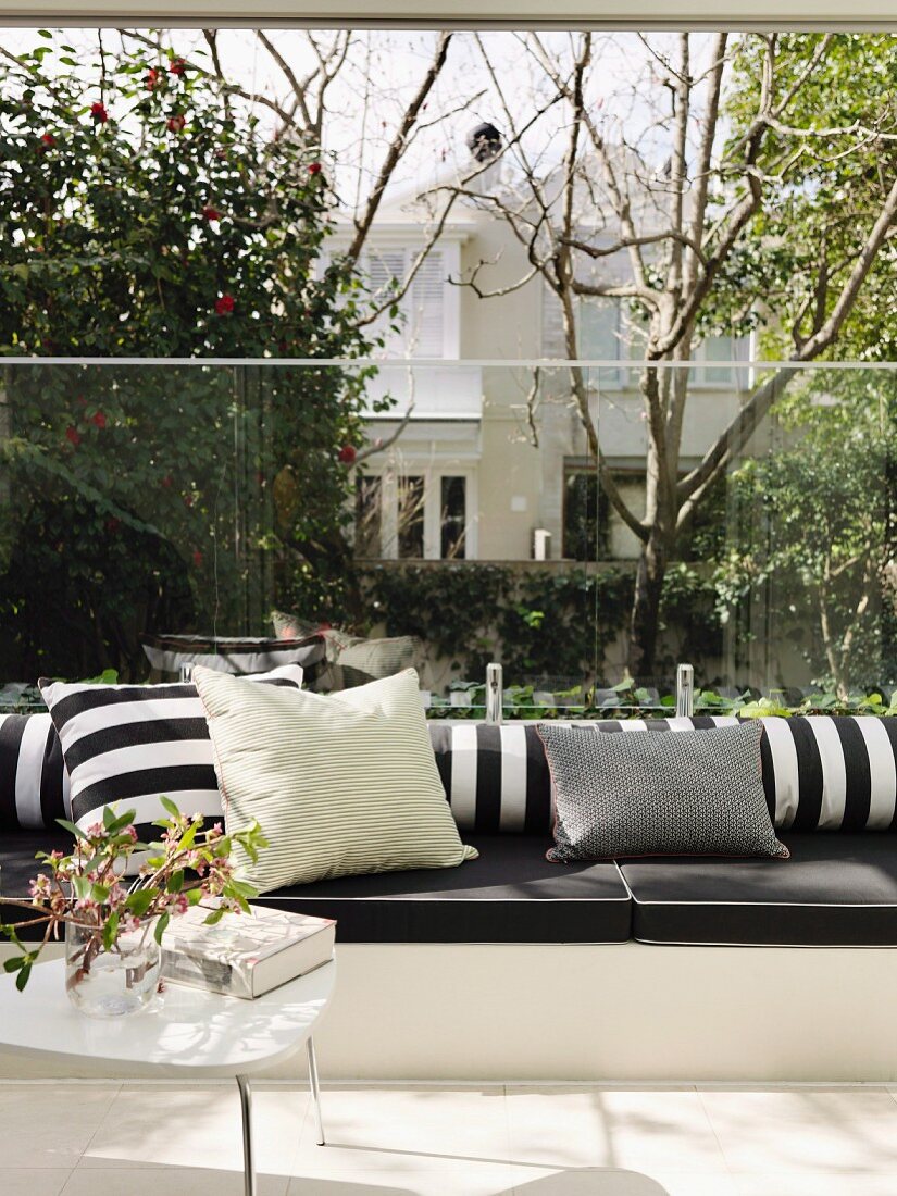 Black and white cushions on masonry bench with glass panel as transparent backrest