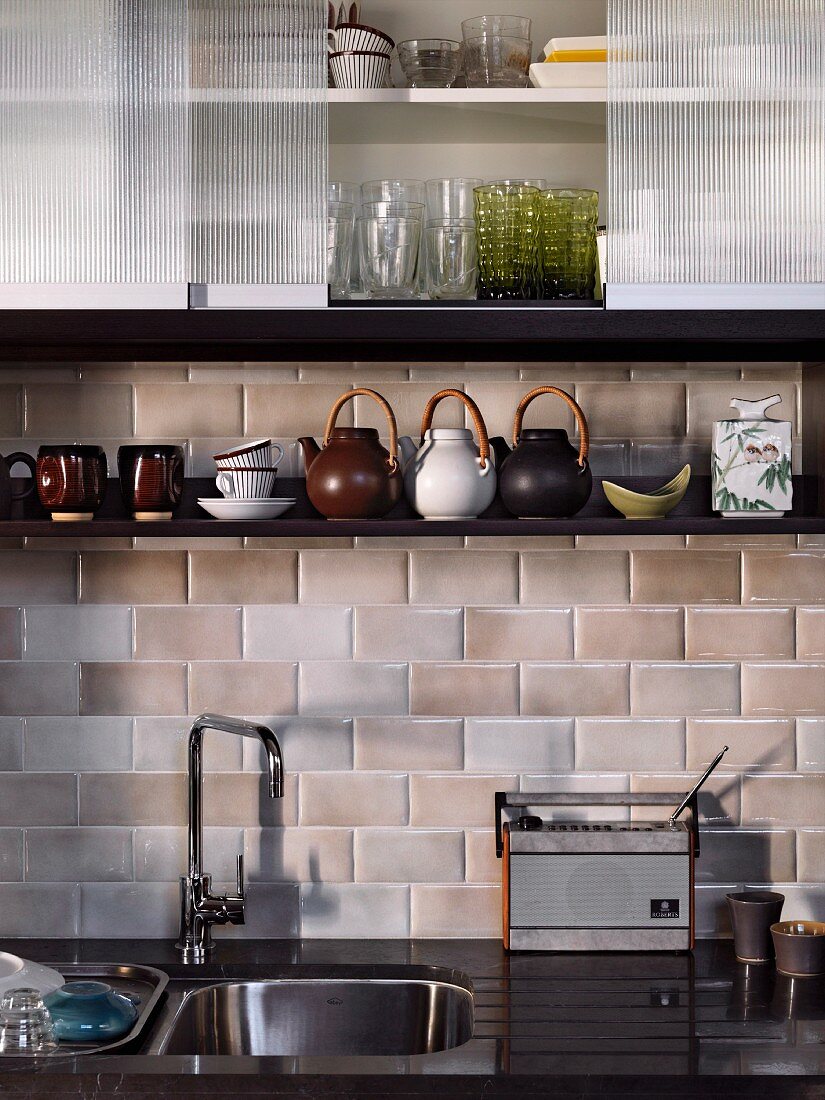 Detail of retro kitchen counter below tiled wall and wall units