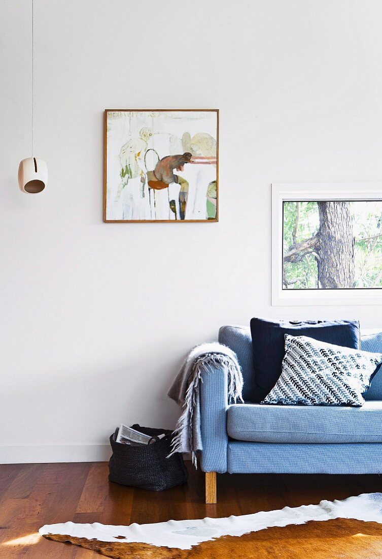 Window and picture on white wall above sofa with scatter cushions