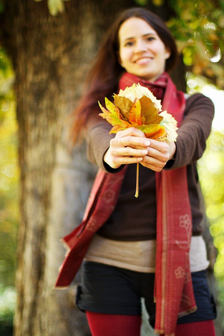 Junge Frau mit Herbstblättern
