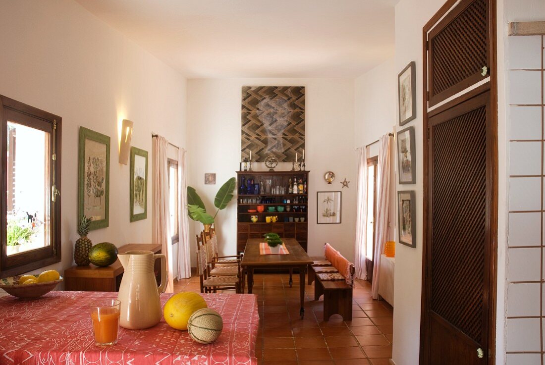 Offener Wohnraum mit langer Esstafel und halb offenem Geschirrschrank mit darüberhängendem modernen Bild