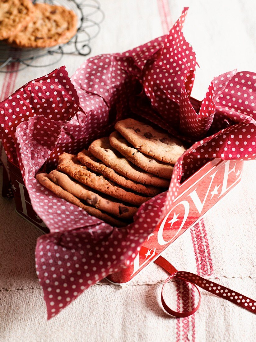 Chocolate chip cookies in a biscuit tin lined with a red and white napkin