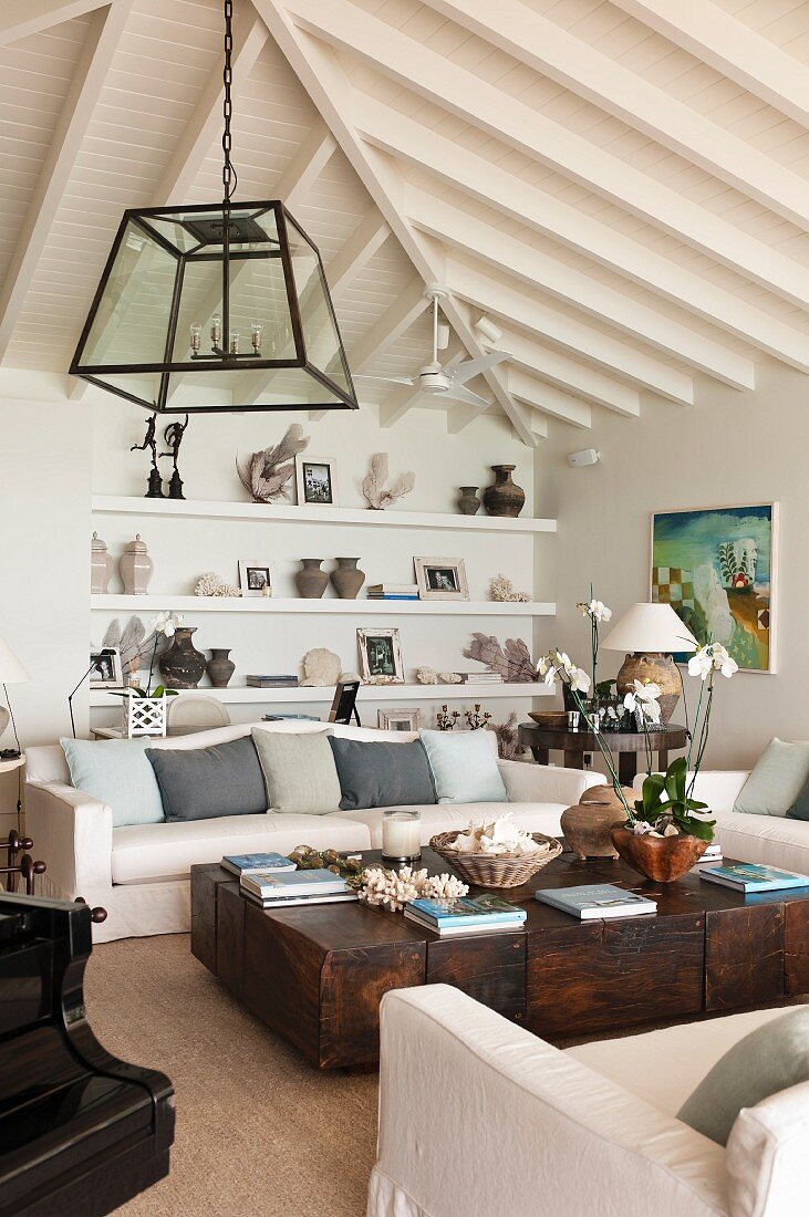 Bright, attic living room with solid wood, antique coffee table and objet d'art on shelving