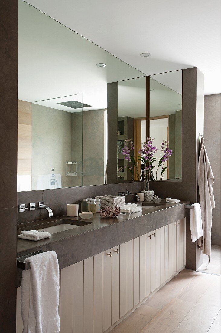 Huge mirror in modern bathroom with two sunken sinks in stone washstand