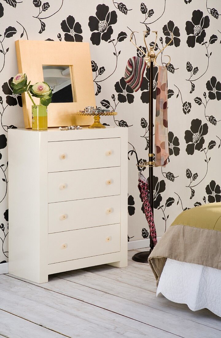 Chest of drawers against floral wallpaper