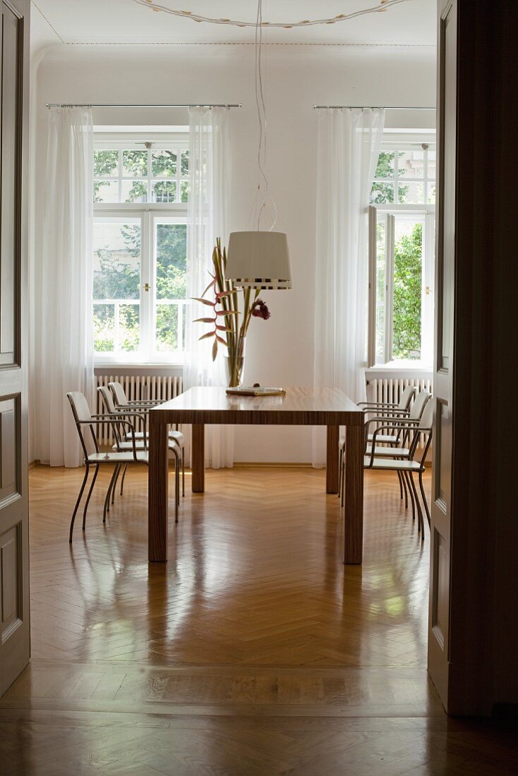 View of modern dining table and chairs in classic setting through doorway