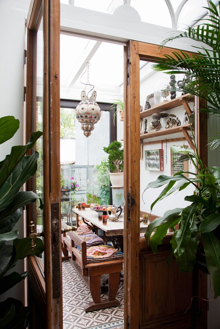 View through wooden door with glass panels into African-style dining room