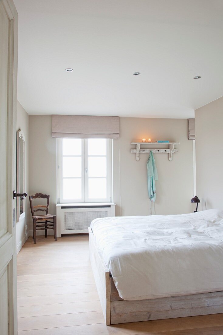 Cheerful bedroom with pale wooden floor and simple bed frame in pale wood