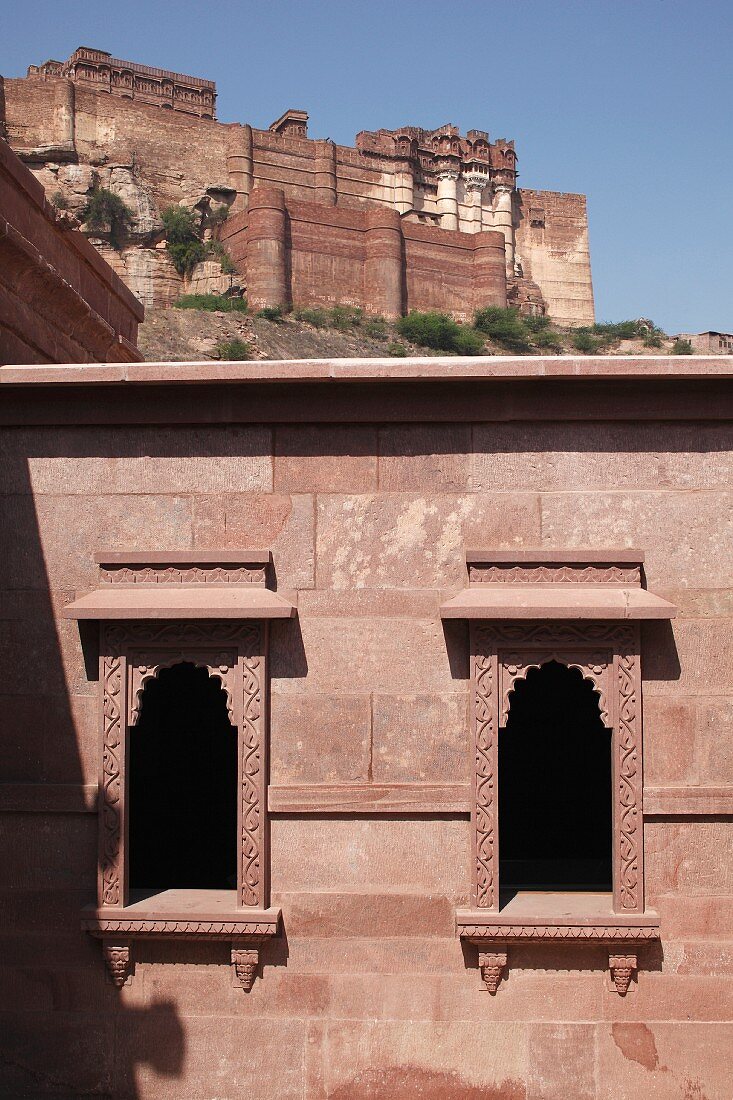 Exterior facade and windows of Raas Haveli Hotel, Jodhpur, India with view of mountain fortress