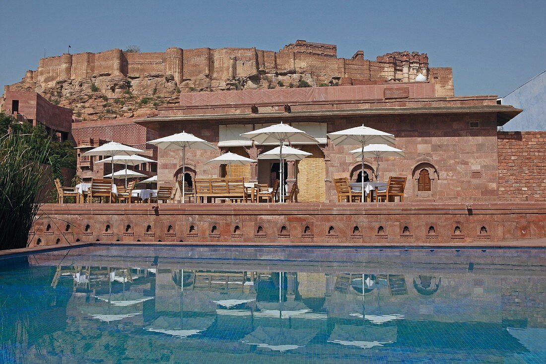 Restauranttische und Sonnenschirme beim Swimmingpool vom Hotel Raas Haveli, Jodhpur, Indien