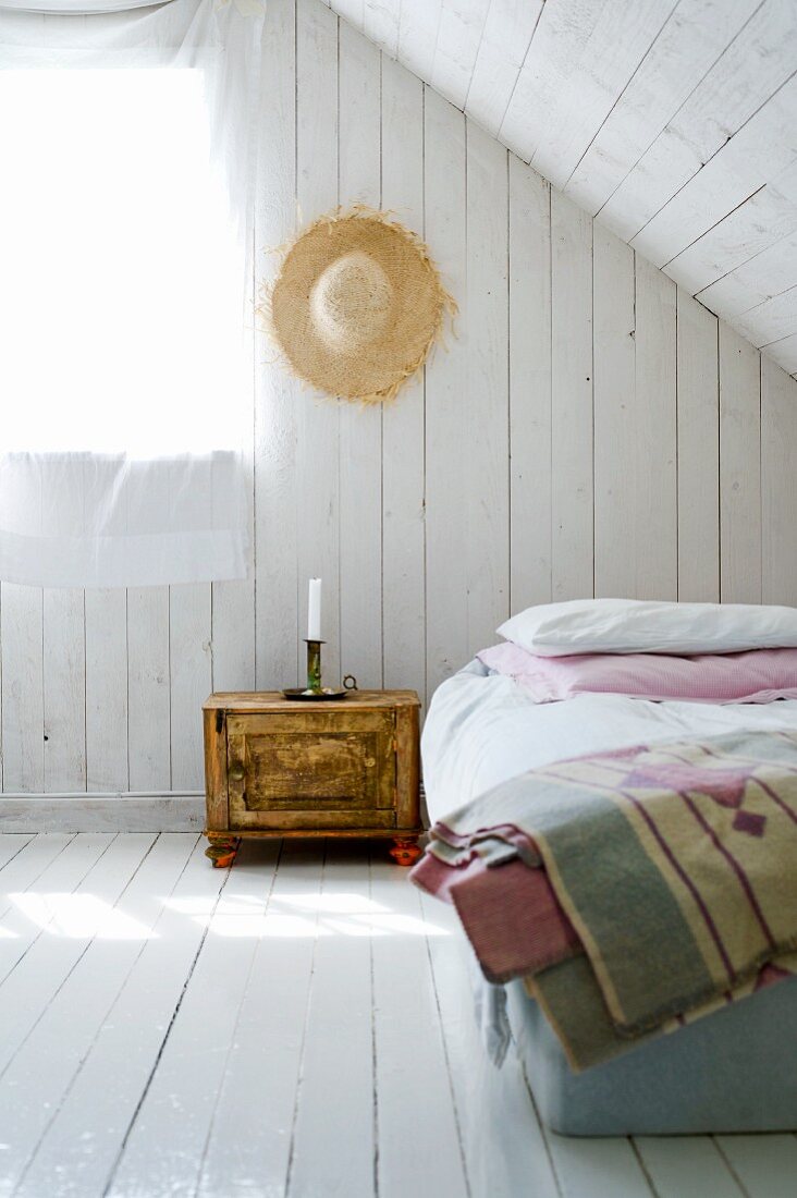 Schlichtes Dachzimmer mit weiss gestrichenen Holzdielen an Wand und Boden