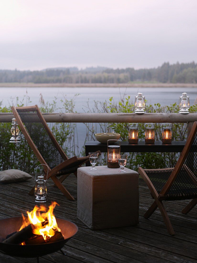 Terrasse mit Liegestühlen, Feuerkorb und Windlichtern am See
