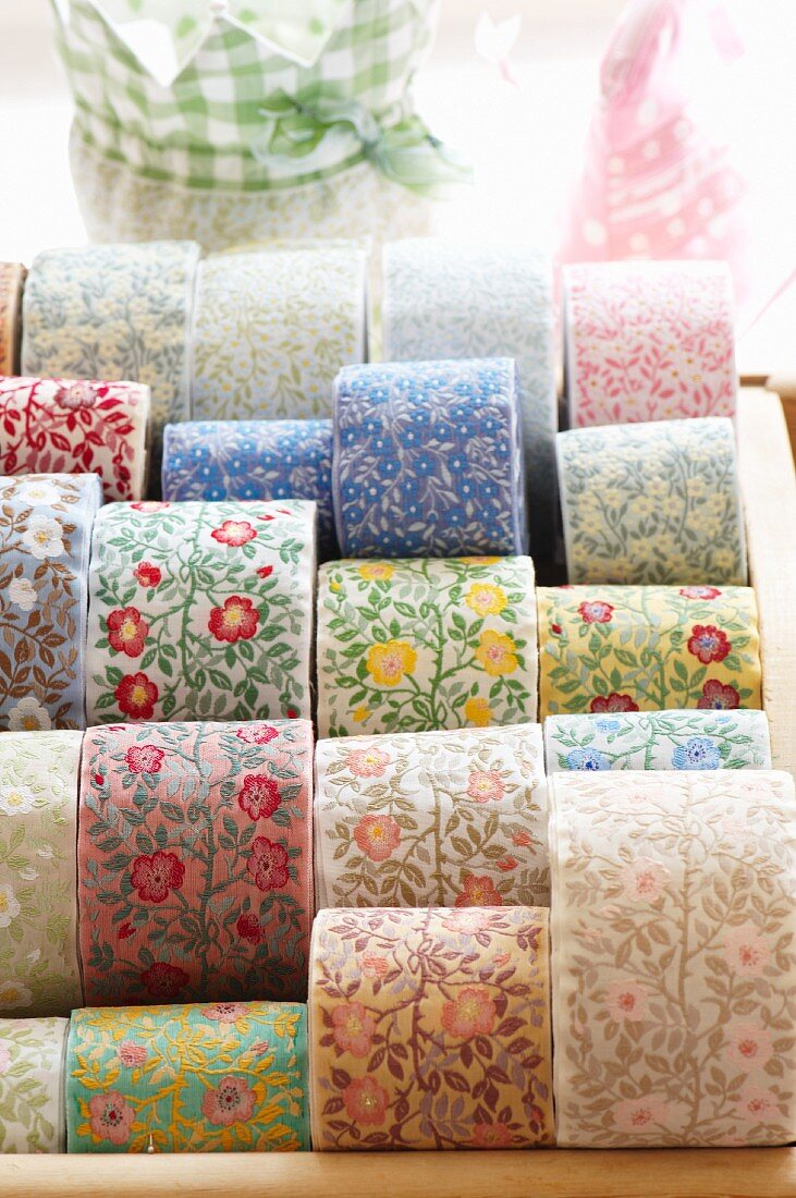 Rolls of woven ribbons with floral motifs in various colours