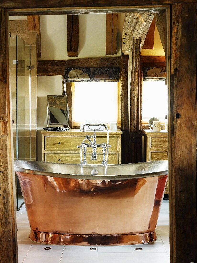 Blick durch offene Tür auf freistehende Kupfer Badewanne im Vintagestil in ländlichem Ambiente