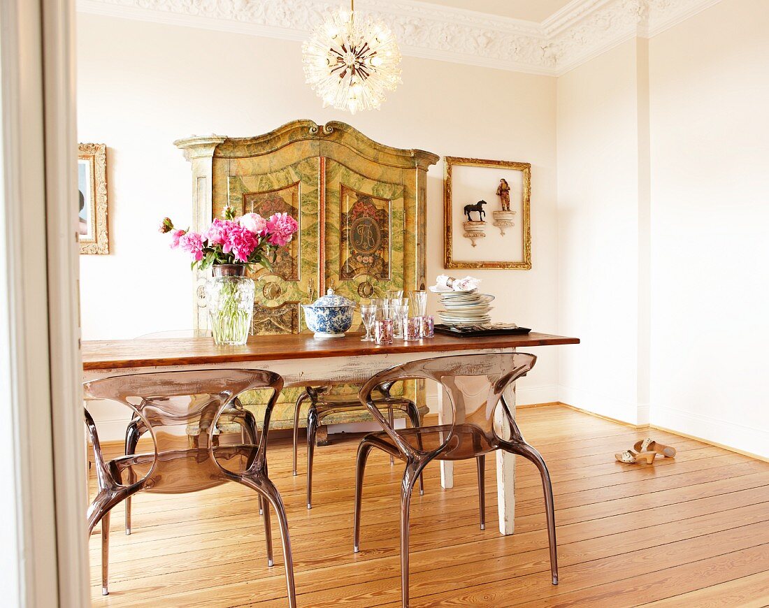 Dining table, postmodern plexiglass chairs and antique-effect cupboard