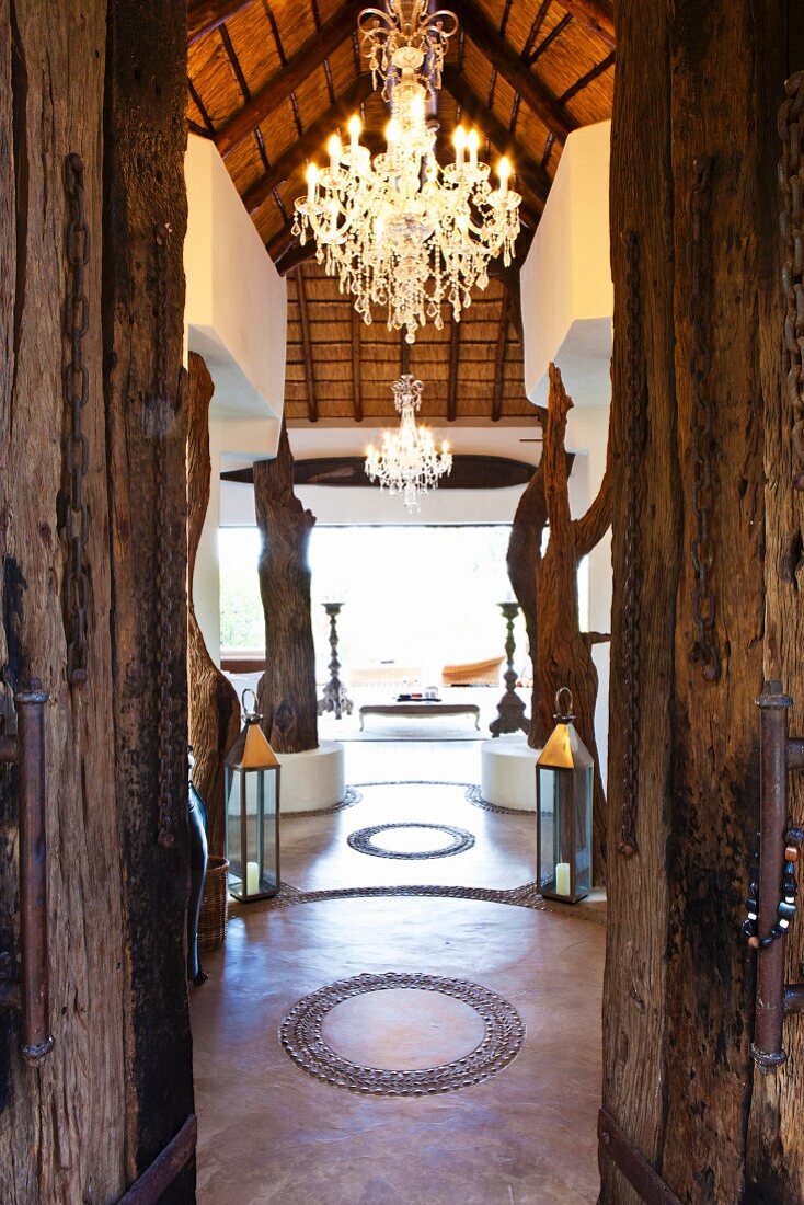 View through rustic wooden door into temple-like interior with large chandelier