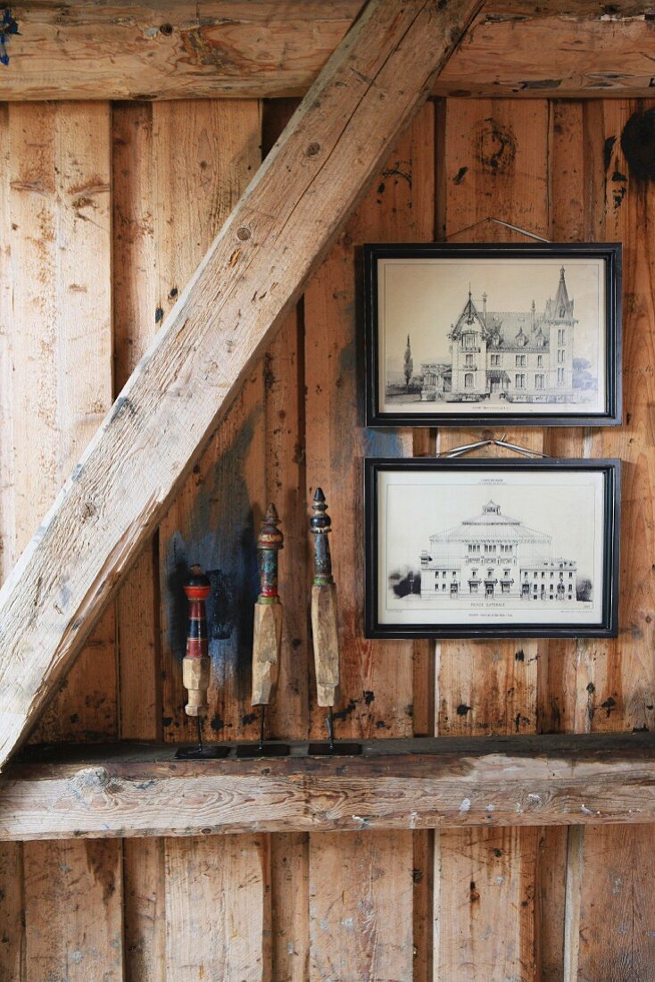 Bilder hängen an einer Holzwand, Holzbalken dienen als Ablage für Dekoobjekte