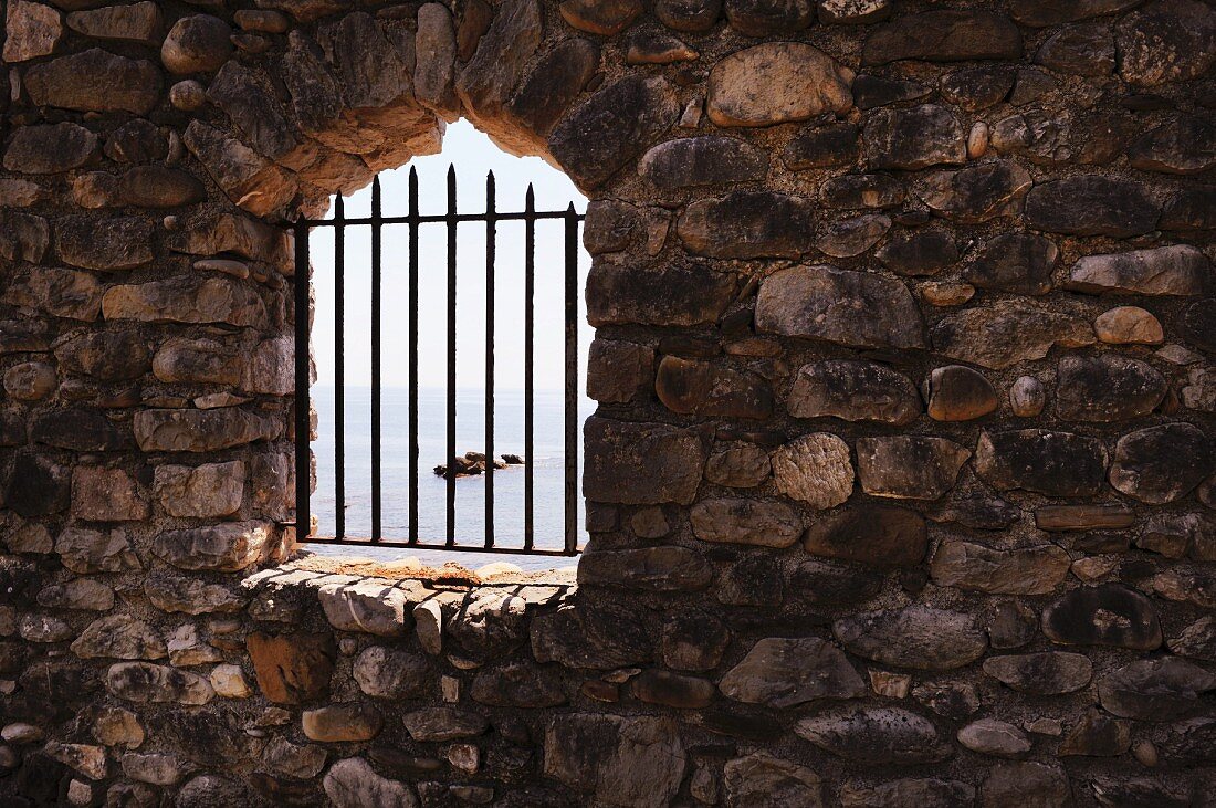 Barred, arched window opening in stone wall