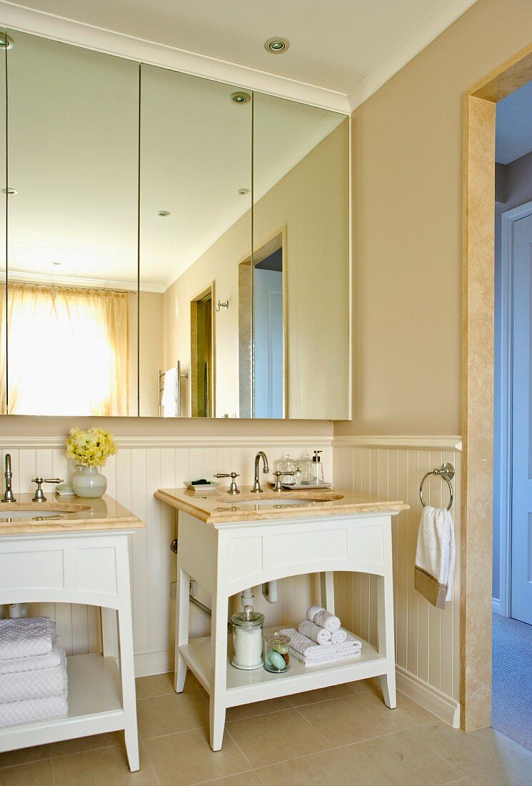 Bright bathroom with separate wash stands and mirrored bathroom cabinet