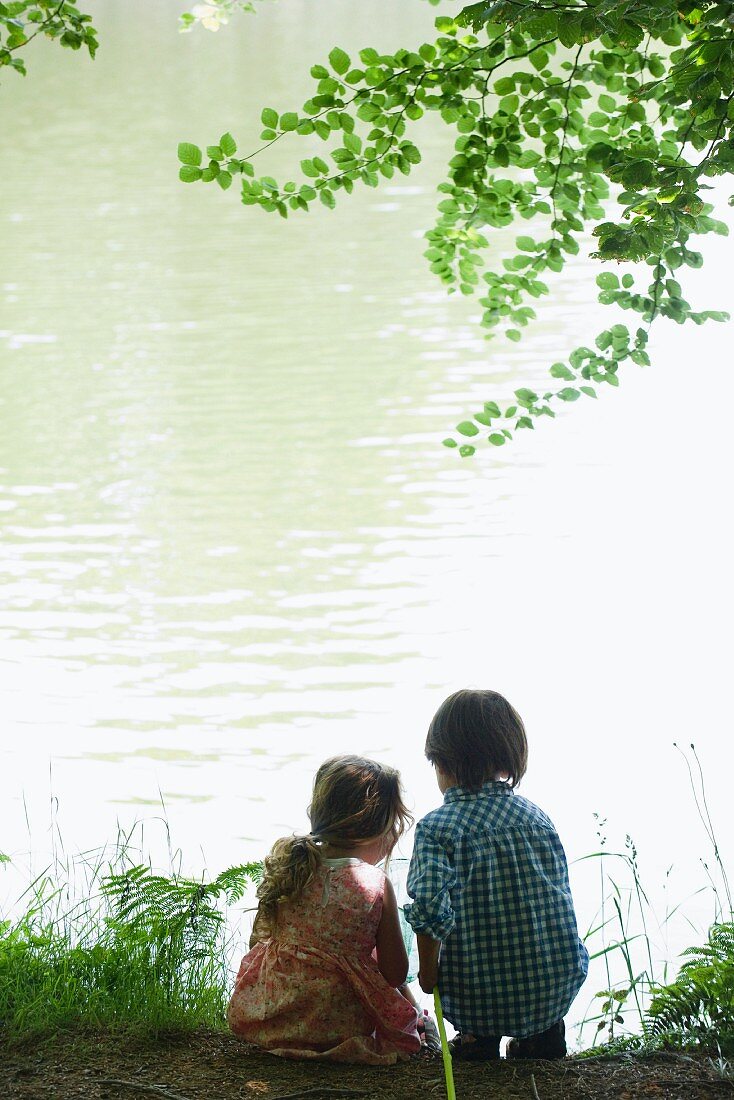 Girl and boy fishing on lake shore