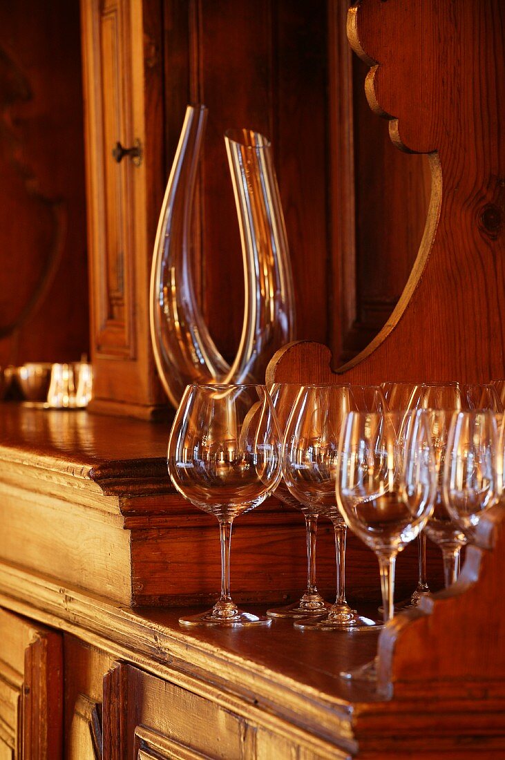 Simple, modern wine glasses and elegant carafe on antique dresser (Schloss Schauenstein)