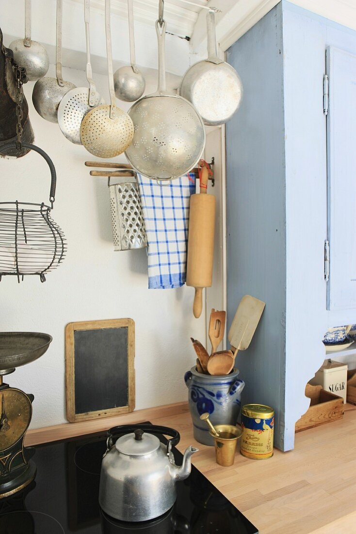 Modern meets old in a simple kitchen with a ceramic hob and antique cooking utensils