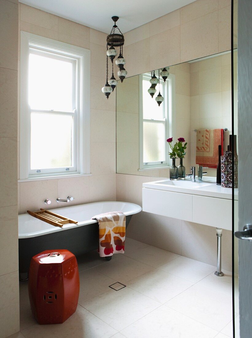 View through open door into modern bathroom with vintage bathtub below window