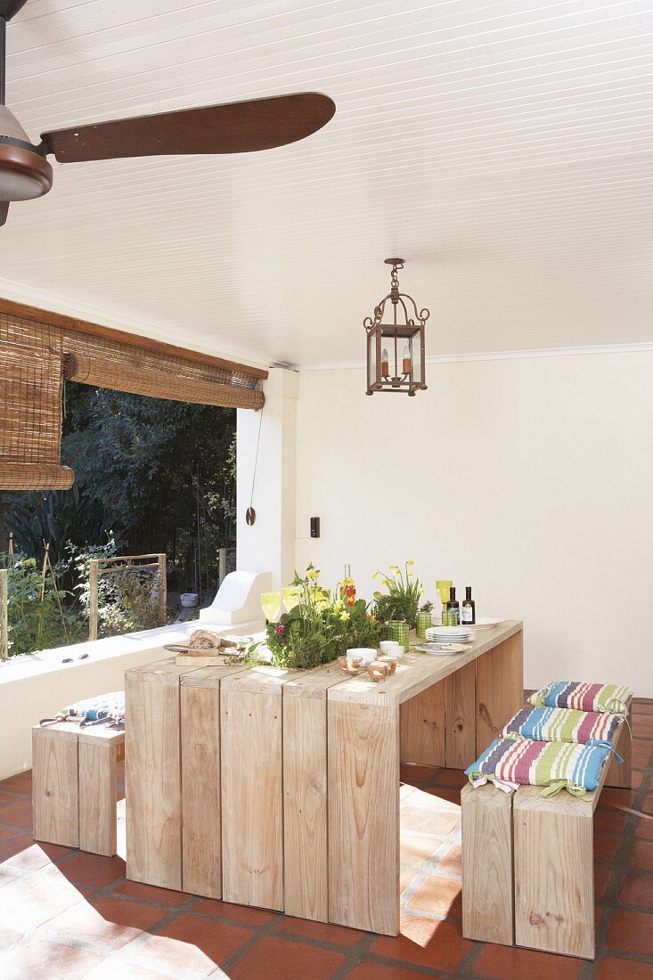 Frühlingsdeko auf rustikalem Outdoortisch mit Holzbänken in Loggia