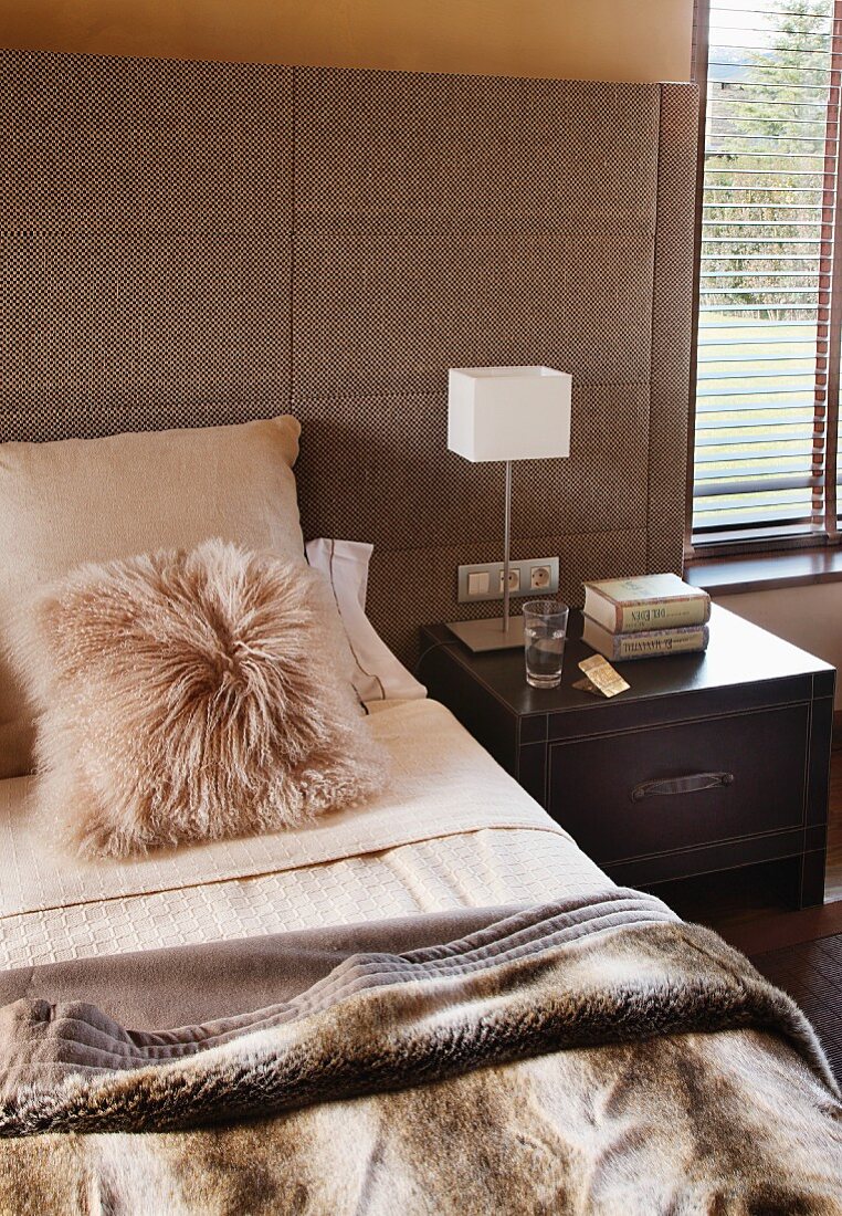 Naturtöne im Schlafzimmer - Fellkissen und Kuscheldecke auf Doppelbett mit breit gepolstertem Kopfteil