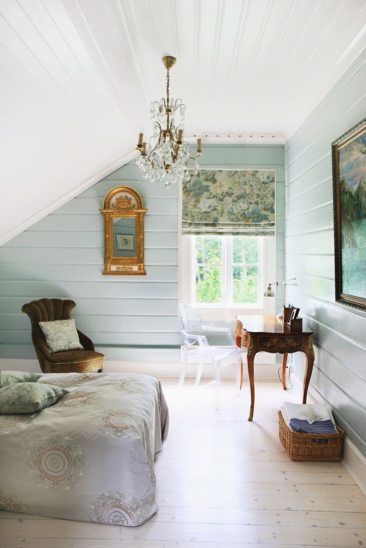 Attic bedroom with chandelier, gilt-framed mirror and antique furnishings
