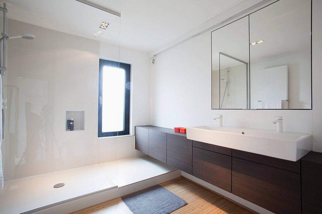 Elegantes Designerbad mit grosszügigem Duschbereich und durchgehendem Unterschrank unter überkragendem Waschbecken