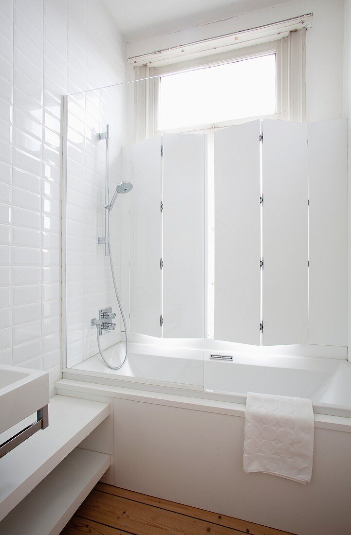 Duschbadewanne und Glasabtrennung vor Altbaufenster mit innenliegenden Klappläden
