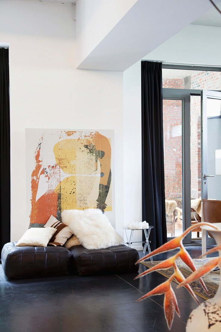 Comfortable loft atmosphere - modern painting behind collection of scatter cushions on leather floor cushions