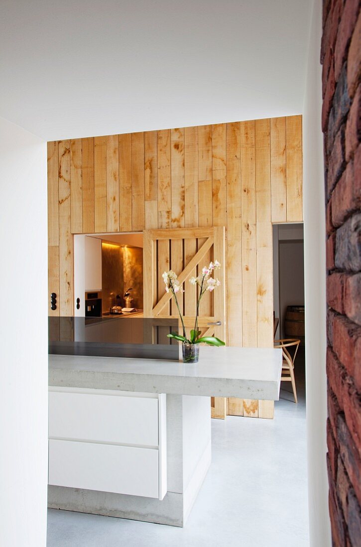Küchentheke aus Beton mit eingebautem Unterschrank und Schubladen vor Holzwand