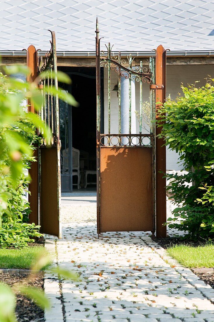 Open garden gate with view of house with veranda