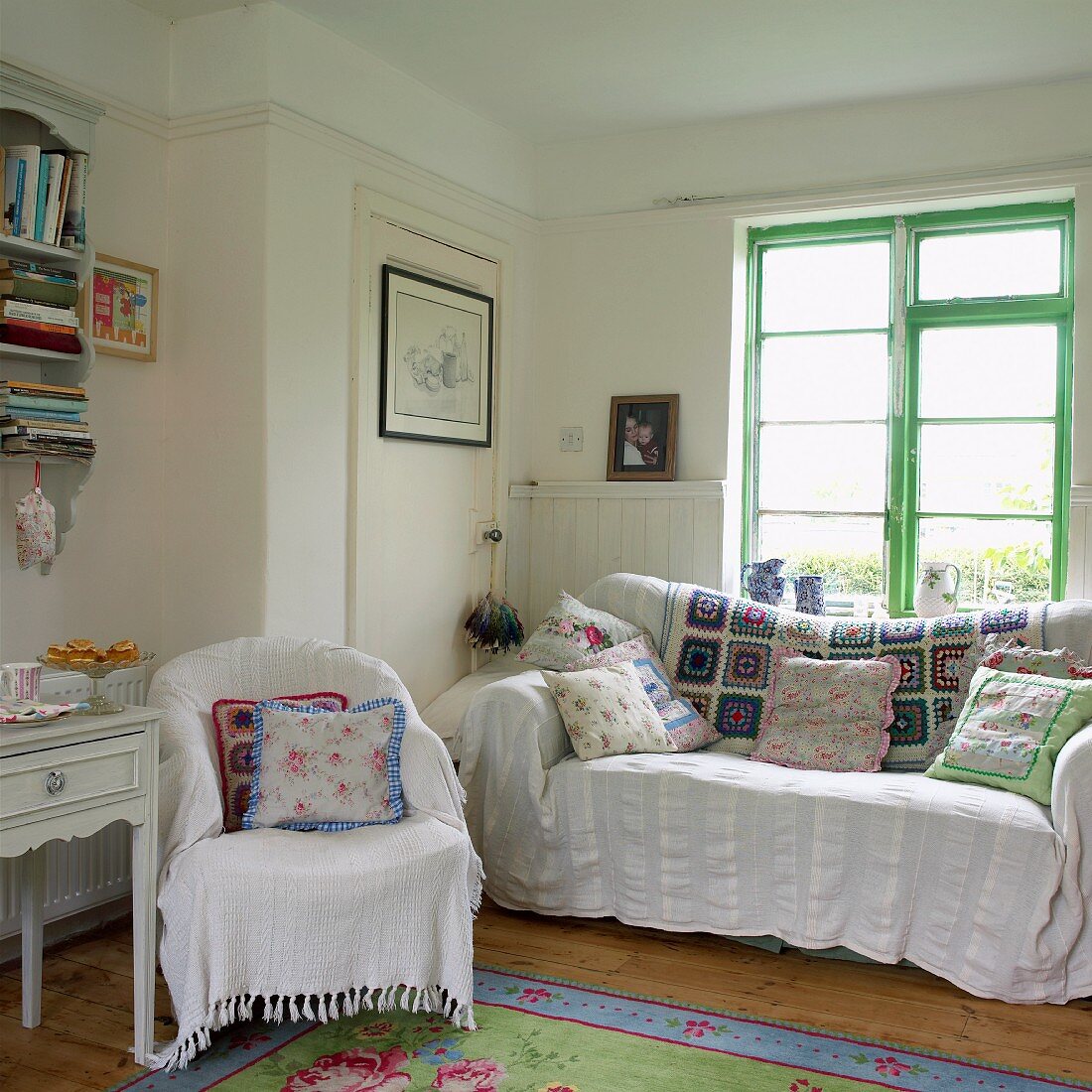 Wohnzimmer im Landhausstil mit weissen Decken, Patchwork und geblümten Kissen auf Sessel und Sofa