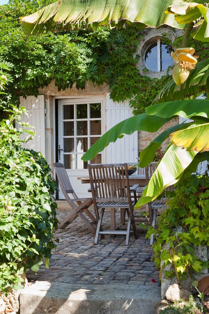 View from garden to terrace with wooden furniture adjoining house with lattice door