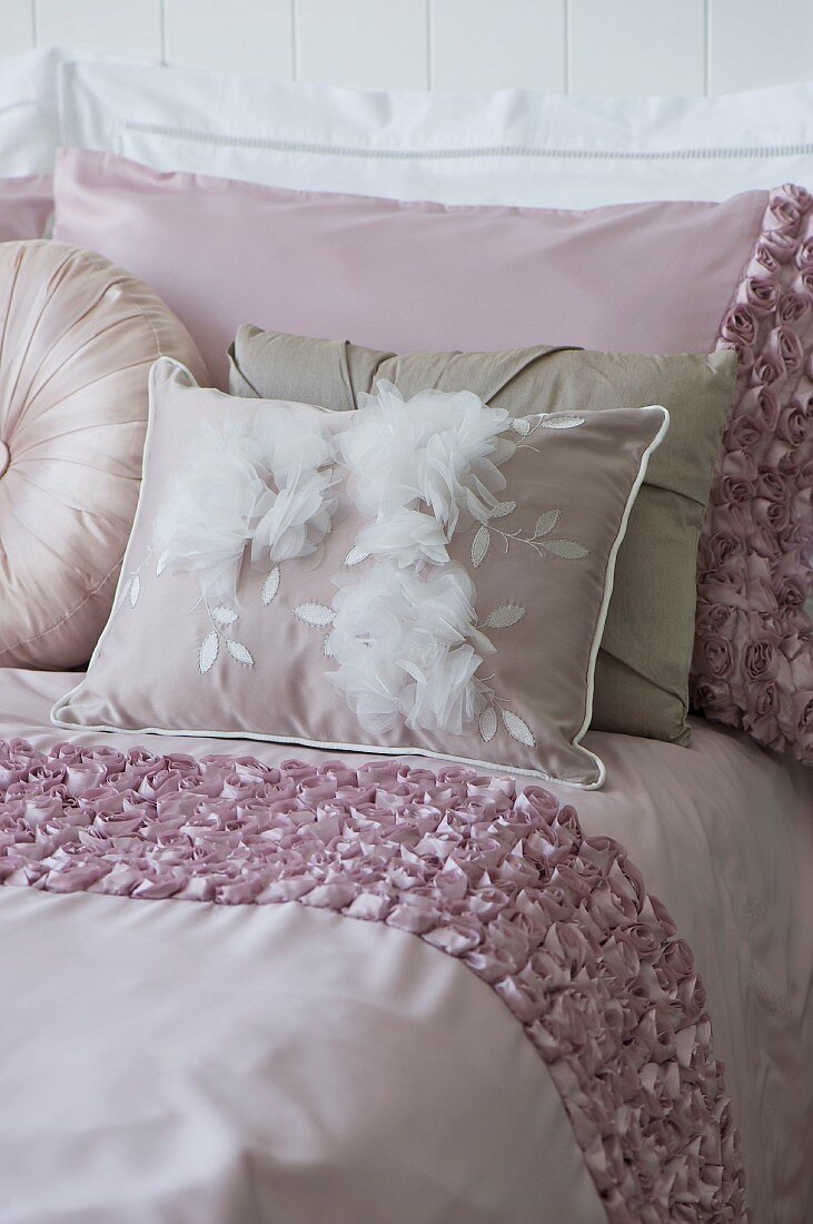 Pale pink bedspread, pillows and scatter cushions on bed