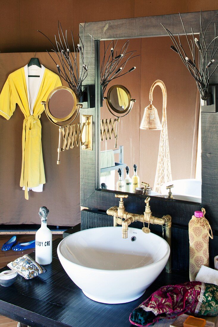 Waschtisch mit Waschschüssel vor Spiegel und im Hintergrund aufgehängter Bademantel an Stellwand
