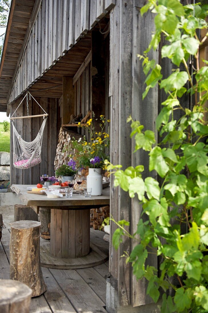 Flowers on wooden table and tree stump stools on terrace of wooden cabin