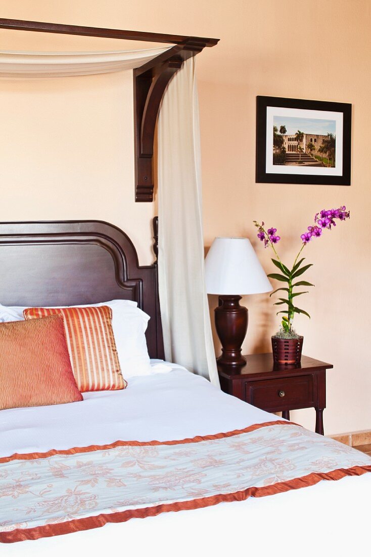 Rosafarbenes Schlafzimmer mit Edelholzbett und Nachttischlampe mit Holzfuss