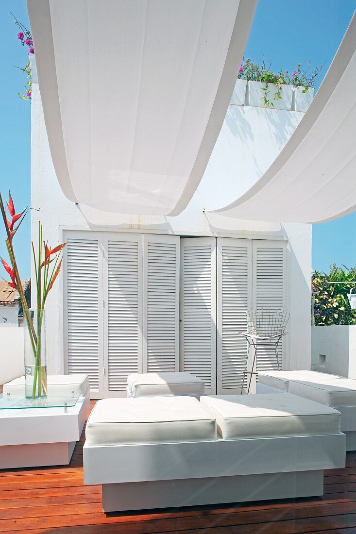 Elegant outdoor furniture with white leather upholstery under white awnings on roof terrace