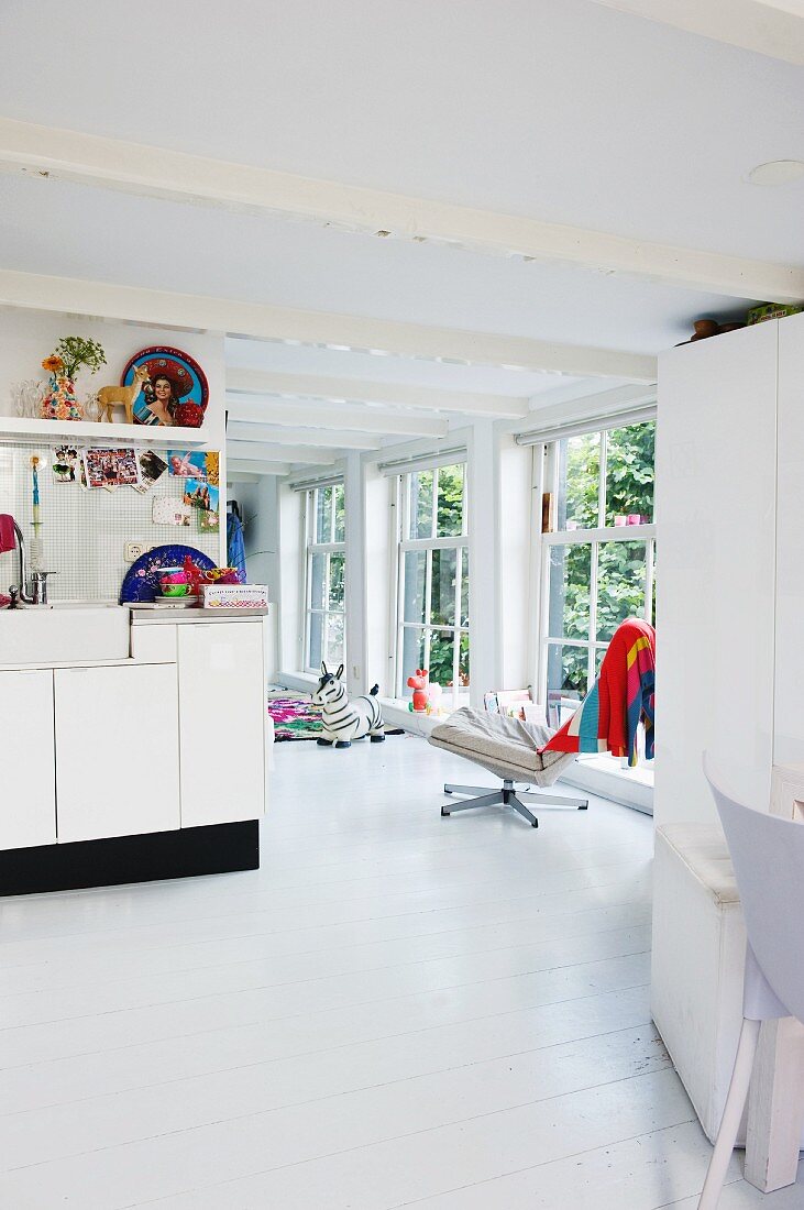 Offener Wohnraum in Weiß mit einzelnen, bunten Dekorationsstücken