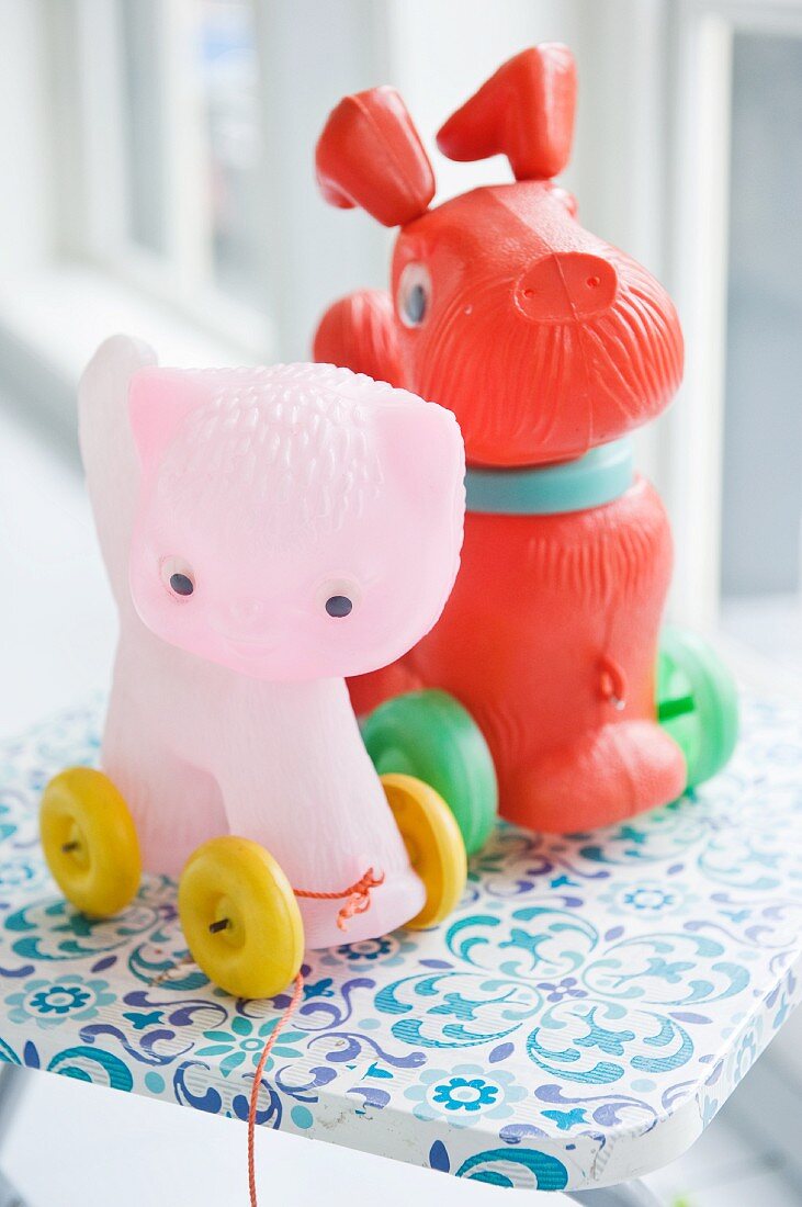 Plastic, pull-along dog and cat-shaped toys on wheels