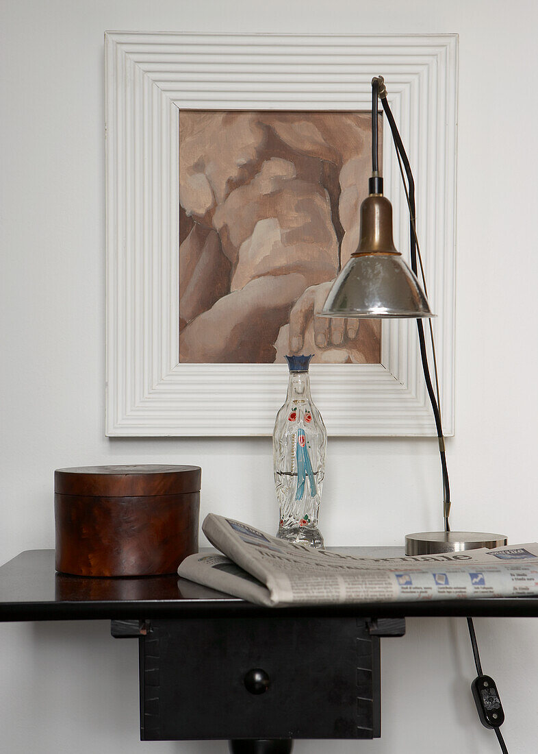 Desk lamp next to vintage bottle on black console table